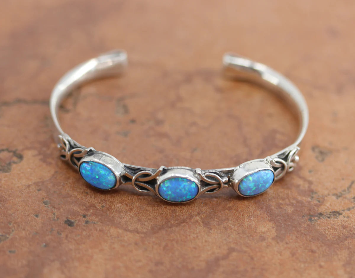 Navajo Native American bracelet by Thomas Yazzie. It is made from sterling silver and created opal. It is about 5 1/4" around and 3/8" wide. The opening is about 1", and it is partly flexible.